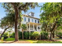 Charming two-story home with a porch, lush landscaping, and inviting curb appeal nestled among mature trees at 1878 Headquarters Plantation Dr, Johns Island, SC 29455