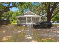 Charming gray cottage-style home with a quaint front porch and mature trees at 2170 Midland Park Rd, North Charleston, SC 29406