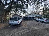 Front exterior of a home with large trees and a gravel driveway and a screened porch at 6385 Sc-162, Hollywood, SC 29449