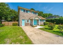 Charming brick home featuring a long driveway, lush green lawn, and unique turquoise shutters and doors at 1369 Miles Dr, Charleston, SC 29407