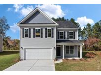 Charming two-story home featuring a gray exterior, a two-car garage and well-manicured landscaping at 206 Palfrey Dr, Ridgeville, SC 29472