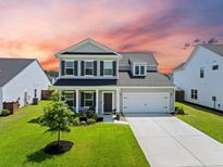 Inviting two-story home featuring a manicured lawn and attached two-car garage at 291 Lucca Dr, Summerville, SC 29486