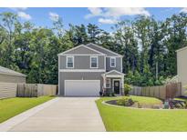 Charming two-story home featuring a well-manicured lawn, attached two car garage, and inviting front porch at 352 Matuskovic Dr, Charleston, SC 29414