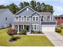 Inviting two-story home featuring a manicured lawn and a two-car garage at 354 Beachgrass Ln, Summerville, SC 29486
