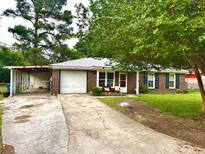 Charming brick home featuring a well-manicured lawn, attached garage, and covered carport, perfect for southern living at 4470 Farmwood Ct, Ladson, SC 29456
