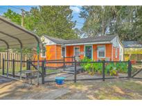 Charming single-story home featuring an orange exterior, fenced yard and covered parking at 4928 Durant Ave, North Charleston, SC 29405