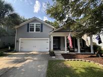 Charming two-story home with gray siding, a two-car garage, and a welcoming front porch with American flags at 5008 W W Liberty Meadows Dr, Summerville, SC 29485