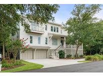 Beautiful multi-story home with a three-car garage and lush landscaping enhancing its curb appeal at 55 Seagrass Ln, Isle of Palms, SC 29451