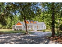 Charming two-story home with a large front porch and beautiful landscaping nestled among mature trees at 7986 Highway 162, Hollywood, SC 29449