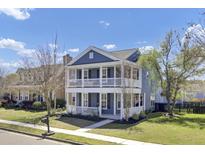 Charming two-story home with a double porch, well-maintained landscaping, and a beautiful blue exterior on a sunny day at 117 Red Leaf Blvd, Moncks Corner, SC 29461