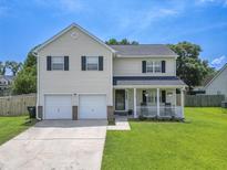 Charming two-story home with a well-manicured lawn, a covered front porch, and a two car garage at 1350 Pinyon Pine Dr, Ladson, SC 29456