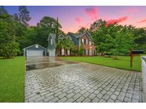 Charming two-story home with brick and siding, lush landscaping, and a spacious driveway with a detached garage at 138 Shadowmoss Pkwy, Charleston, SC 29414