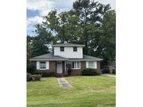 Charming two-story brick home with lush green lawn and mature trees in a quiet neighborhood at 1674 Garden St, Charleston, SC 29407