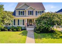 Charming two-story home with a well-manicured lawn, flowering trees, and welcoming front porch at 173 Silver Cypress Cir, Summerville, SC 29485