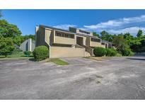 Inviting exterior of a multi-story tan home with landscaped bushes and nearby trees under a bright, sunny, blue sky at 2334 Treescape Dr # 2006, Charleston, SC 29414
