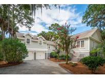 Charming home featuring a two-car garage, complemented by lush landscaping and beautiful crape myrtle trees at 2645 Gnarled Pine, Seabrook Island, SC 29455