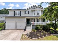 Charming two-story home boasts a welcoming porch, well-maintained lawn, and a two-car garage at 3038 Penny Ln, Johns Island, SC 29455