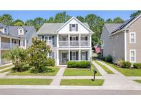 Charming two-story home featuring a double front porch, well-manicured lawn, and traditional American flag at 578 Delafield Dr, Summerville, SC 29483