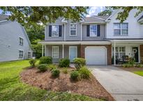 Charming two-story townhouse featuring a light blue front door, white garage door, and well-manicured landscaping at 8721 Grassy Oak Trl, North Charleston, SC 29420