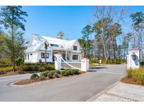 Beautiful exterior shot of a two-story home with a white metal roof and black trim and white picket fence at 105 Peninsula Dr, Ravenel, SC 29470