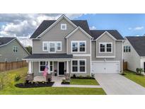 Charming two-story home with gray siding, front porch, manicured lawn, and a two-car garage at 1115 Fitzgerald Ct, Summerville, SC 29485