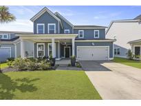 Charming two-story home with blue siding, a two-car garage, and a welcoming front porch with seating at 120 Haverhill St, Summerville, SC 29486