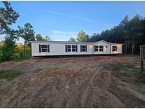 New manufactured home with dark shutters on a spacious lot surrounded by mature trees under clear skies at 1420 Rehoboth Rd, Cottageville, SC 29435