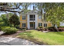 Inviting yellow two-story home with a screened porch, surrounded by lush landscaping and mature trees at 1915 Chatelain Way, Mount Pleasant, SC 29464