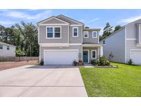 Charming two-story home with light gray siding, a manicured lawn, and a welcoming blue front door at 331 Saddlewood Dr, Charleston, SC 29414