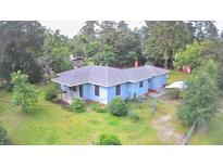 Charming one-story home with a blue exterior and a lush, green lawn surrounded by mature trees at 365 W Pine St, Varnville, SC 29944