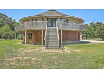 Unique round house featuring a brick base and a wooden balcony surrounding the second story at 395 Summerset Ln, Summerville, SC 29483