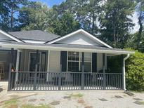Charming home featuring a cozy front porch and gray siding, surrounded by lush greenery at 687 Ponderosa Dr, Charleston, SC 29414