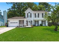 Charming two-story home featuring a well-manicured lawn, inviting front porch, and classic architectural details at 8475 N Scotts Mill Dr, North Charleston, SC 29420