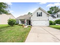 Charming home featuring a well-manicured lawn, two-car garage and classic American flag displayed on the front porch at 9616 Pebble Creek Blvd, Summerville, SC 29485