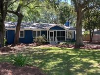 Charming blue cottage with a screened-in porch and lush green lawn shaded by mature trees at 10 Chapman Ave, Isle of Palms, SC 29451
