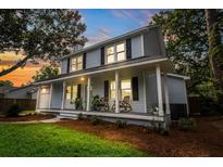 Charming two-story home featuring a welcoming front porch, rocking chairs, and meticulous landscaping at 2020 Piper Dr, Charleston, SC 29407