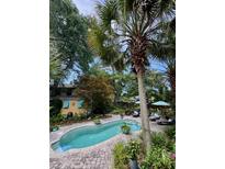 A backyard pool is surrounded by a brick patio, tropical foliage, and mature trees at 2066 Wappoo Dr, Charleston, SC 29412