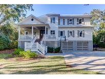 Stunning two-story home featuring elevated construction, a basketball hoop, and a three-car garage at 2414 Goldbug Ave, Sullivans Island, SC 29482
