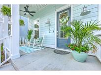 Inviting front porch with rocking chairs, ceiling fan, and decorative plants offering a relaxing outdoor space at 312 Cypress Knee Landing, Summerville, SC 29483