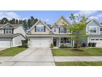 Charming two-story home with a well-manicured lawn, inviting front porch, and a two-car garage at 317 Whispering Breeze Ln, Summerville, SC 29486