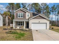 Charming two-story home featuring a manicured lawn, two-car garage, and solar panels on the roof at 324 Spruce Ivy St, Moncks Corner, SC 29461