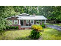 Charming brick home with a metal roof, inviting front porch and well-manicured lawn at 416 Altman St, Moncks Corner, SC 29461