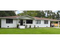 Charming one-story home with white brick exterior, well-manicured lawn, and covered carport at 702 N N Palmetto St, Summerville, SC 29483