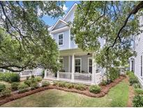 Charming blue two-story home featuring a cozy front porch and beautifully landscaped yard at 1052 Avenue Of Oaks, Charleston, SC 29407