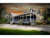 Charming home featuring a spacious screened-in porch with ceiling fans and a well-manicured yard at 153 Willow Brook Way, Cordesville, SC 29434