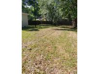 View of a spacious backyard with green grass and mature trees, surrounded by a wood fence at 1612 Evergreen St, Charleston, SC 29407