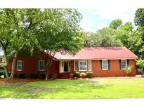 Charming brick home featuring a red metal roof, well-manicured lawn, and mature trees at 2206 Hunter Creek Dr, Charleston, SC 29414