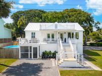 Charming two-story white home with a spacious deck and a screened-in porch at 2407 Cameron Blvd, Isle of Palms, SC 29451