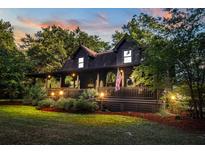 Charming log home with covered porch, manicured lawn, and warm exterior lighting at 24678 Augusta Hwy, Cottageville, SC 29435