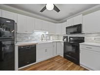 Updated kitchen featuring white cabinets, black appliances, and stylish backsplash at 252 Howle Ave # C3, Charleston, SC 29412